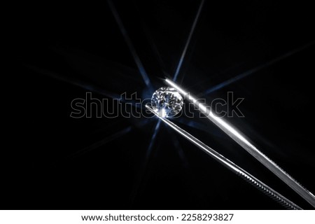 Diamond selective focus held in metal jeweller tweezers, brilliant stone cut with star shape light ray burst, starburst or sunbeam. Inspection of polish quality and contamination. Carbon material. Stock foto © 
