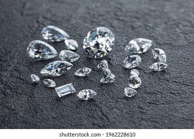 Diamonds of different cuts and sizes lie on dark background top view.