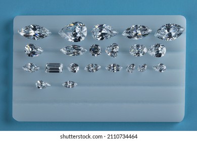 Diamonds laid out on stand for sorting polished diamonds by shape and size at workplace. Top view on blue background.