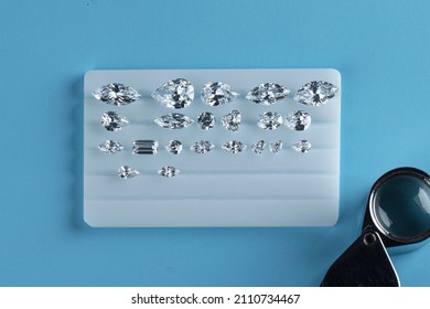 Diamonds laid out on stand for sorting polished diamonds by shape and size at workplace. Top view on blue background.
