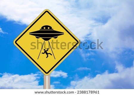 Diamond-shaped crossing sign with yellow background and black border with an Alien Abduction in the middle.