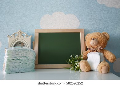 Diapers and blank chalkboard. Teddy bear dressed in diaper. frame with a copy space