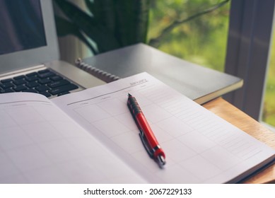 Diary and 2022 Calendar for Planner to management daily agenda, appointment, and timetable for a job. Laptop and book placed on office desk. Working online at home Concept.