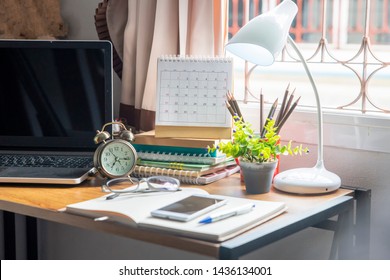 Diary And Book On School Desk For Student, Study For Exam. Wooden Table With Desktop Laptop, Notebook, Book, Pencils, Diary, Notepad, Clock And White Lamp, Working Space At Home