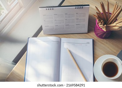 Diary, Calendar and agenda for Event Planner to plan timetable, appointment, organization, management on office table. Desktop Calender and coffee place on wooden desk. Calendar Background Concept