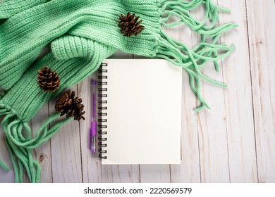 Diary Or Journaling Flat Lay, Top Down View With Blank Notebook, Pen, Pine Cones And A Teal Cable Knit Scarf