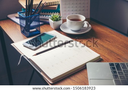 Diary and notebook for Planner to plan agenda, reminder, timetable, daily appointment, management on table. Calender, laptop, smartphone and cup of coffee place on office desk. work online at home
