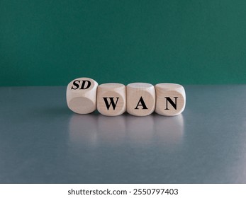 Dice form the expression SD WAN. Symbol for Software defined Wide Area Networking. Beautiful green background, grey table. Copy space.