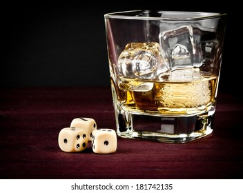 dice near whiskey glass on old wood table, concept of game