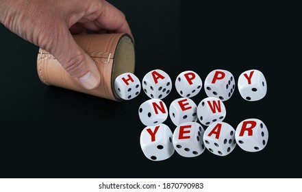 Dice Spelling Happy New Year When Tumbling Out Of A Raffle Cup Hold By One Hand On Black Background. Good Luck And Wealth Concept.