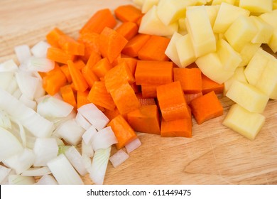 Diced carrots & diced potatoes with diced onion on a cutting board