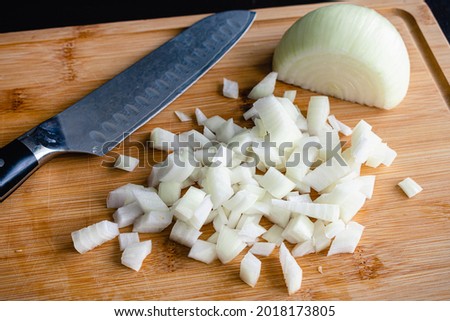 Diced onion with a chef's knife on a bamboo chopping board