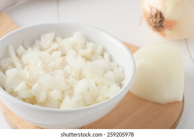 Diced Onion In A White Bowl On A Round Wooden Board