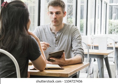 Dicussing a financial document and signing a business contract in cafe in midday. - Shutterstock ID 1104727436