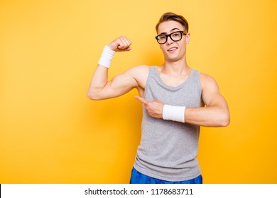 Did You See It? Portrait Of Funny Youngster Man Show Biceps On Hand, Arm Isolated On Bright Yellow Background