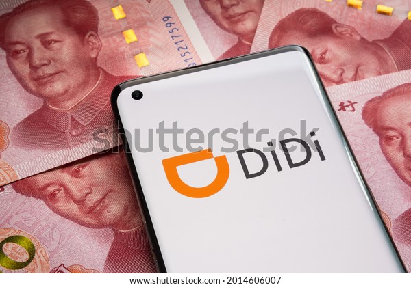 Didi car hire company logo seen on smartphone\
placed on pile pf 100 yuan banknotes. Concept for share price.\
Stafford, United Kingdom, July 26,\
2021.