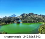 Dieng, Wonosobo, Indonesia, 17 July 2024 - Enjoying a beautiful morning view of Telaga Warna Lake in in Dieng Plateau with sunny day, trees and valley