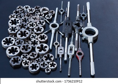 A Lot Of Dies And Holders For Them Of Different Sizes For Threading In Metal, On A Black Background.