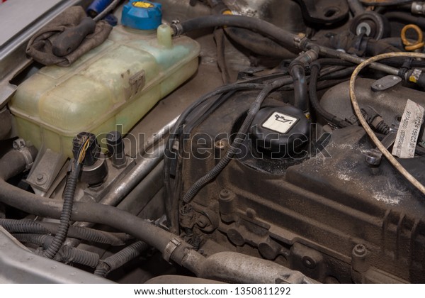 Diesel engine in the car and plastic water\
reservoir. Dirty old diesel\
engine