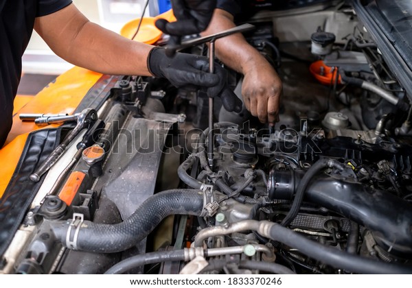 Diesel engine during service, or maintenance at the\
garage. The internal design of the old engine. Mechanical guy using\
a screwdriver to remove nuts from the engine box. Engine car spare\
part