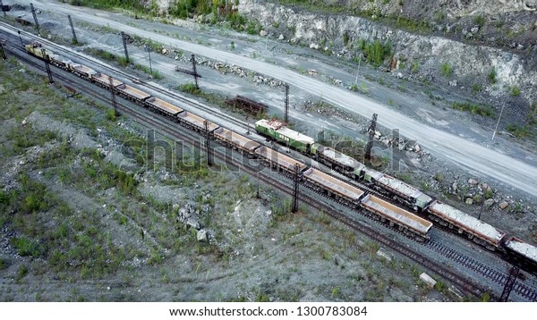 Diesel\
locomotive is pushing dump-car filled with rubble stone in the\
background of a quarry for limestone\
mining