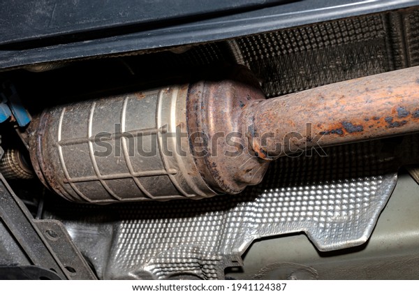 A diesel particulate\
filter in the exhaust system in a car on a lift in a car workshop,\
seen from below.