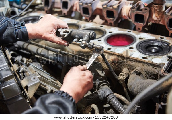diesel truck engine repair service. Automobile\
mechanic tightening using\
wrench