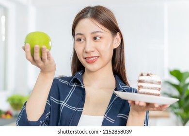 Diet asian young woman lose weight for health choosing to eat green apple, fruit do not choose eat chocolate cake, bakery because will make fat when hungry, female weight loss person, temptation food