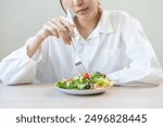 Diet in bored face, unhappy beautiful asian young woman, girl on dieting, holding fork at tomato on salad plate, dislike or tired with eat fresh vegetables. Nutrition of clean, healthy food good taste