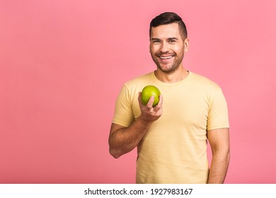 Diet concept. Cheerful beautiful young man eating apple, isolated over pink background. - Powered by Shutterstock