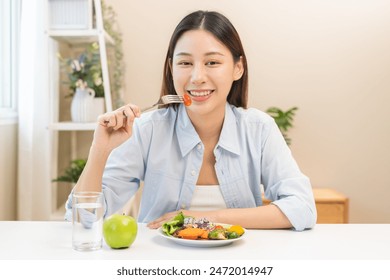 Diet concept, close up young woman hand use fork to prick tomato, fresh vegetable, green salad in plate, eat nutrition food on plate at home, low fat to good body. Girl getting weight loss for healthy - Powered by Shutterstock