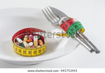 Diet concept. measuring tape wrapped Twith tablets on a plate.