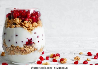 diet dessert with yogurt, granola and pomegranate fruit on white wooden table. healthy breakfast - Powered by Shutterstock