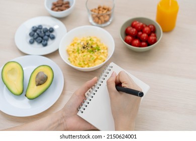 Diet, Dieting hand of asian young woman, girl write diet plan nutrition on table is different food ingredients in the green. Nutritionist of healthy, nutrition of weight loss, health care people.