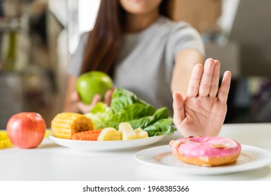 Diet, Dieting young asian woman or girl use hand push out, deny sweet donut and choose green apple, salad vegetables, eat food for good healthy, health when hungry. Close up female weight loss person. - Shutterstock ID 1968385366