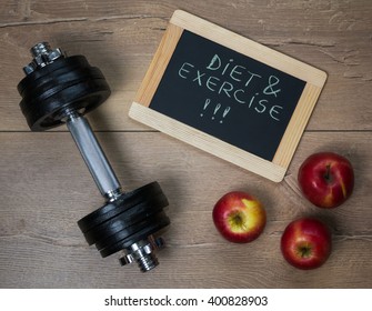 Diet And Exercise Concept. Dumbbell And Red Apples On A Wooden Background