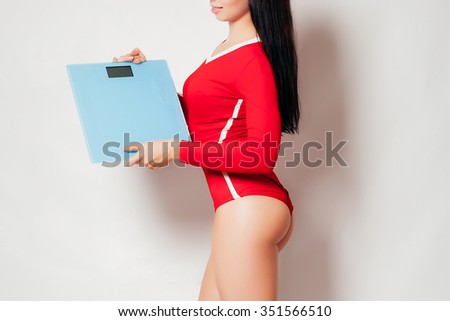 Diet and exercise. Portrait of a young fitness woman holding scales and smiling happily isolated on white copyspace on the side