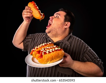 Diet failure of fat man eating fast food hot dog on plate. Breakfast for overweight person who greedily eats lot . Junk meal leads to obesity. Enraged by large amount of food fat.