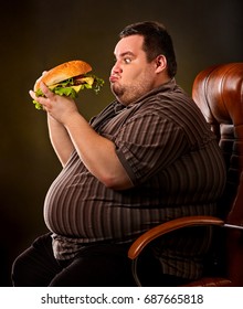 Diet failure of fat man eating fast food hamberger. Happy smile overweight person who spoiled healthy food by eating huge hamburger on fork. Obesity due to eating bad foods. Very fat man eating fast