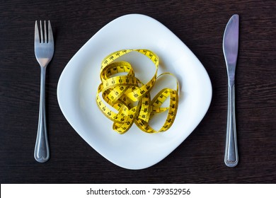 Diet, Healthy Eating, Food And Weigh Loss Concept - Close Up Of Green Apple And Measuring Tape With Salad On Wooden Table