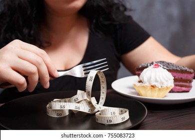 Diet, healthy eating, weight loss and slim body concept. Overweight girl with fork choosing slimness instead of sweets