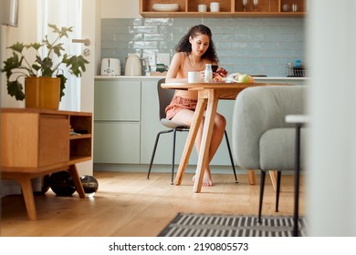 Diet, Healthy Life And Food Of A Hygienic Female Sitting Alone Looking Up Nutrition Value Of An Apple On A Phone. Young Woman At Home Living A Clean, Balanced And Organic Lifestyle In The Kitchen.