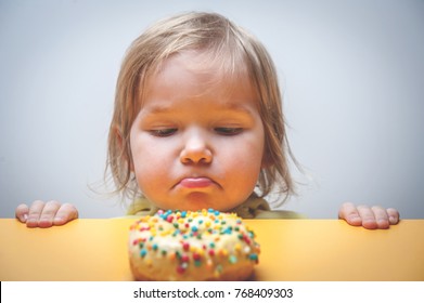 Diet for kids. sad and unhappy child Child reaches donuts. Tasty food for kids. Kid is looking on doughnut. junk food addiction. 