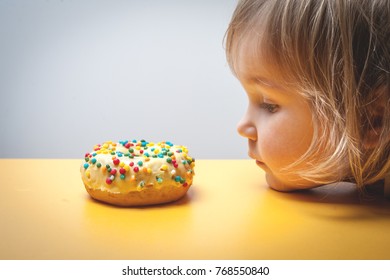 Diet For Kids. Sad And Unhappy Child Child Reaches Donuts. Tasty Food For Kids. Kid Is Looking On Doughnut. Junk Food Addiction. 