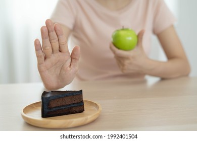 Diet And Lose Weight Concept. Woman Reject To Eat Chocolate Cake And Choose Eat Green Apple For Good Health And Slim Shape. 