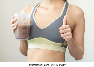 Diet Meal Replacement For Weight Loss, Asian Young Woman In Sportswear, Hand Showing Thumbs Up, Holding Protein Shake Bottle For Drink Supplement For Muscle After Workout At Home. Healthy Body Care.