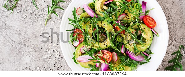 Diet menu. Healthy salad of fresh vegetables -
tomatoes, avocado, arugula, radish and seeds on a bowl. Vegan food.
Flat lay. Banner. Top view