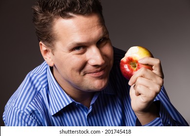 Diet And Nutrition. Happy Young Man Eating Apple Seasonal Fruit On Dark Gray. Guy Recommending Healthy Nutrition.