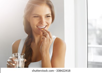 Diet. Nutrition. Healthy Eating, Lifestyle. Close Up Of Happy Smiling Woman Taking Pill With Cod Liver Oil Omega-3 And Holding A Glass Of Fresh Water In Morning. Vitamin D, E, A Fish Oil Capsules.