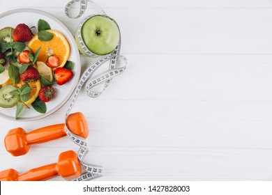 Diet plan, menu or program, tape measure, water, dumbbells and diet food of fresh fruits on white background, weight loss and detox concept, top view - Shutterstock ID 1427828003
